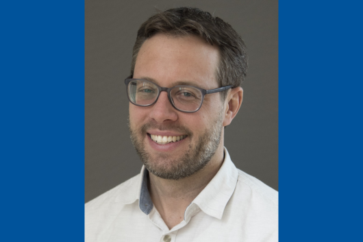 Pictured is Dr. John Doench a man with short dark brown hair light skin wearing glasses and smiling. He is wearing a white button up collared shirt.